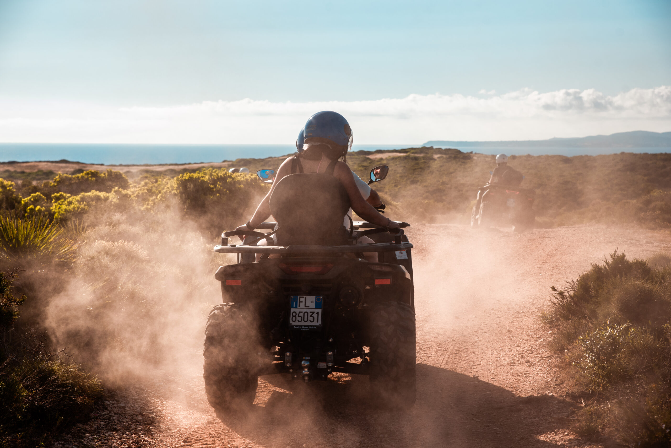 Quad mit Fahrer und Beifahrer auf einem Schotterweg auf Sant'Antioco, Sardinien
